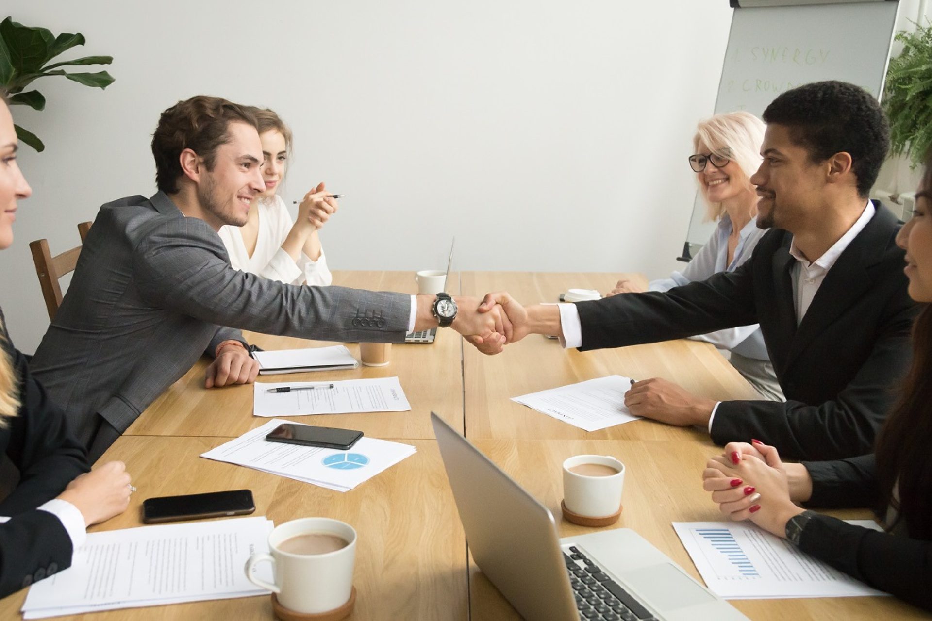 Diverse,Businessmen,Shaking,Hands,After,Signing,Contracts,At,Group,Multiracial